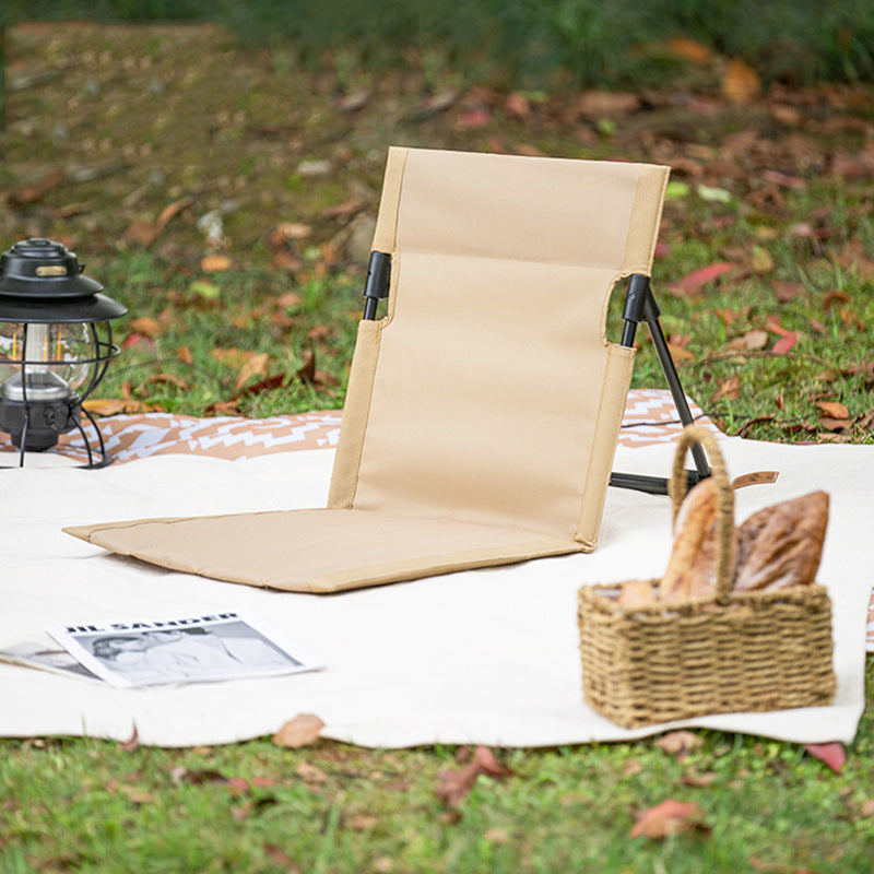 Portable Beige Folding Camping Floor Chair – Lightweight Reclining Outdoor Seat in Campsite